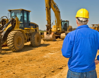 construction worker on a field with heavy machinery equipment