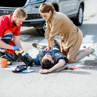 a woman giving first aid to someone injured after a car accident on a job